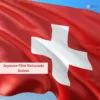 Drapeau de la Suisse flottant au vent sur un ciel bleu clair, symbole de la Fête nationale suisse du 1er août.