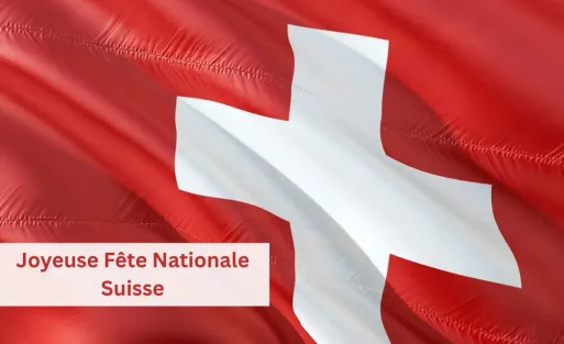 Drapeau de la Suisse flottant au vent sur un ciel bleu clair, symbole de la Fête nationale suisse du 1er août.